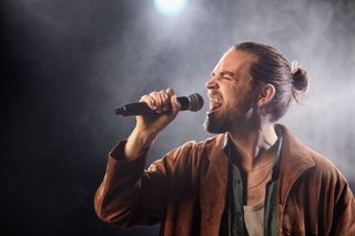 A male rock singer screaming into a Shure microphone.