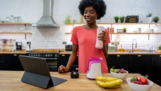 Woman drinking a protein shake in a kitchen