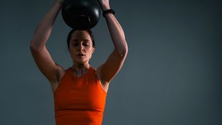 Woman performing kettlebell push press with both hands