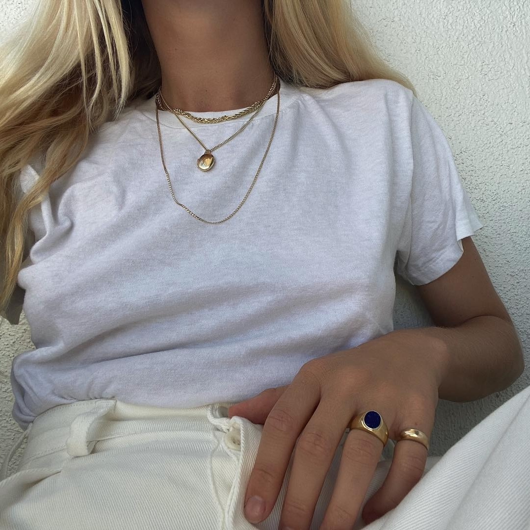 Woman wearing a white t-shirt and gold jewelry.