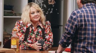 (L to R) Melissa McCarthy as Amily Luck, behind a counter holding a drink talking to Ben Falcone as Clark Thompson in episode 104 of God’s Favorite Idiot