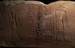A close-up of part of the sarcophagus shows the jackal-headed god Anubis at right and Duamutef, a son of the god Horus, at left. The right-hand column of hieroglyphs contains Horemheb's name and the title of "scribe."