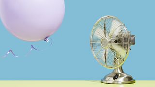 Fan on blue background, blowing a pink balloon