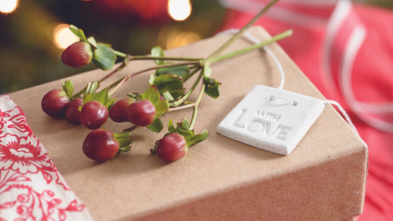 Air dry clay Christmas decoration on brown box with sprig of berries.