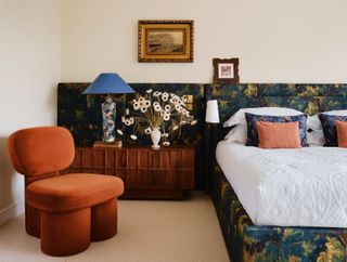 a bedroom with verdure fabric bed and a rust colored chair