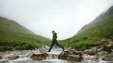 Man walking on stones over a stream