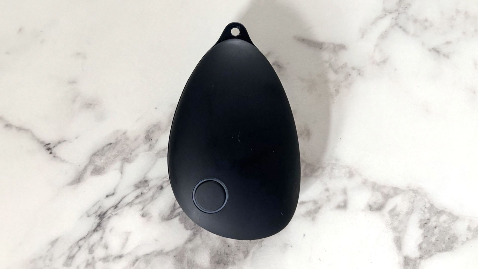 A black, pebble shaped object against a marble backdrop
