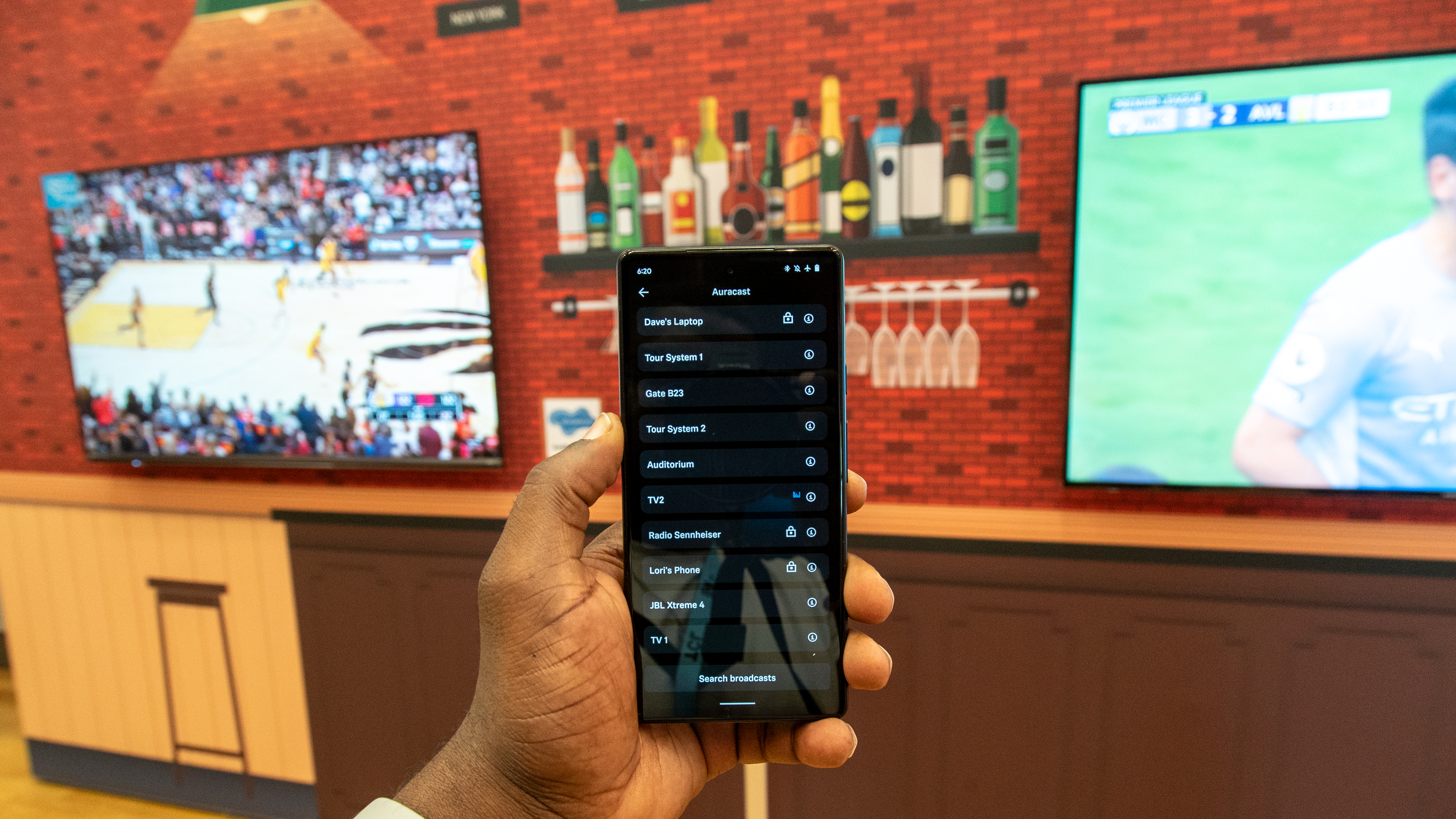 A phone between two TVs broadcasting via Auracast