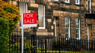 row of stone terraced town houses with for sale sign outside
