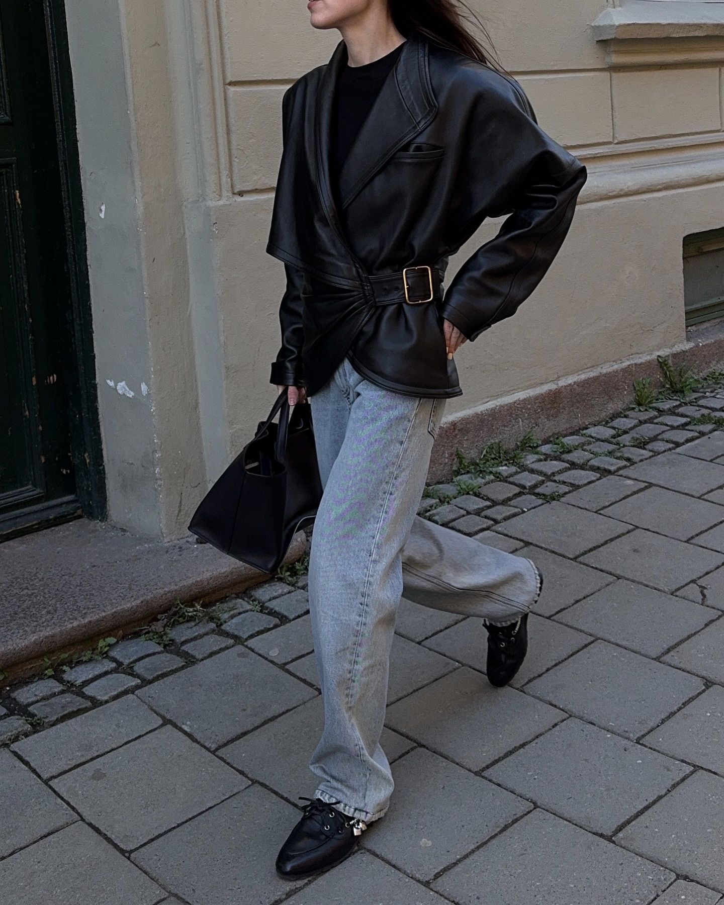 An image of @annabelrosendahl wearing blue jeans with a black leather jacket and deck shoe trainers from Miu Miu.