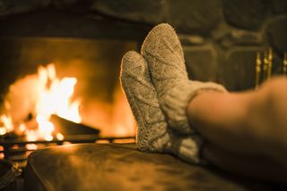 A pair of feet in thick, woollen socks in front of the fire.