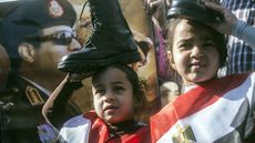 A portrait of Abdel Fattah al-Sisi behind two Egyptian girls