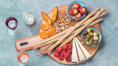Sharing platter of breadsticks, cheese, and fruit