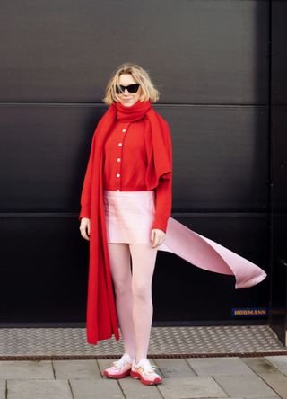 Pernille Rosenkilde wearing a red cardigan and scarf with a baby pink skirt and tights