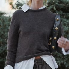 zara model wearing brown fine knit jumper over white shirt with studded black handbag