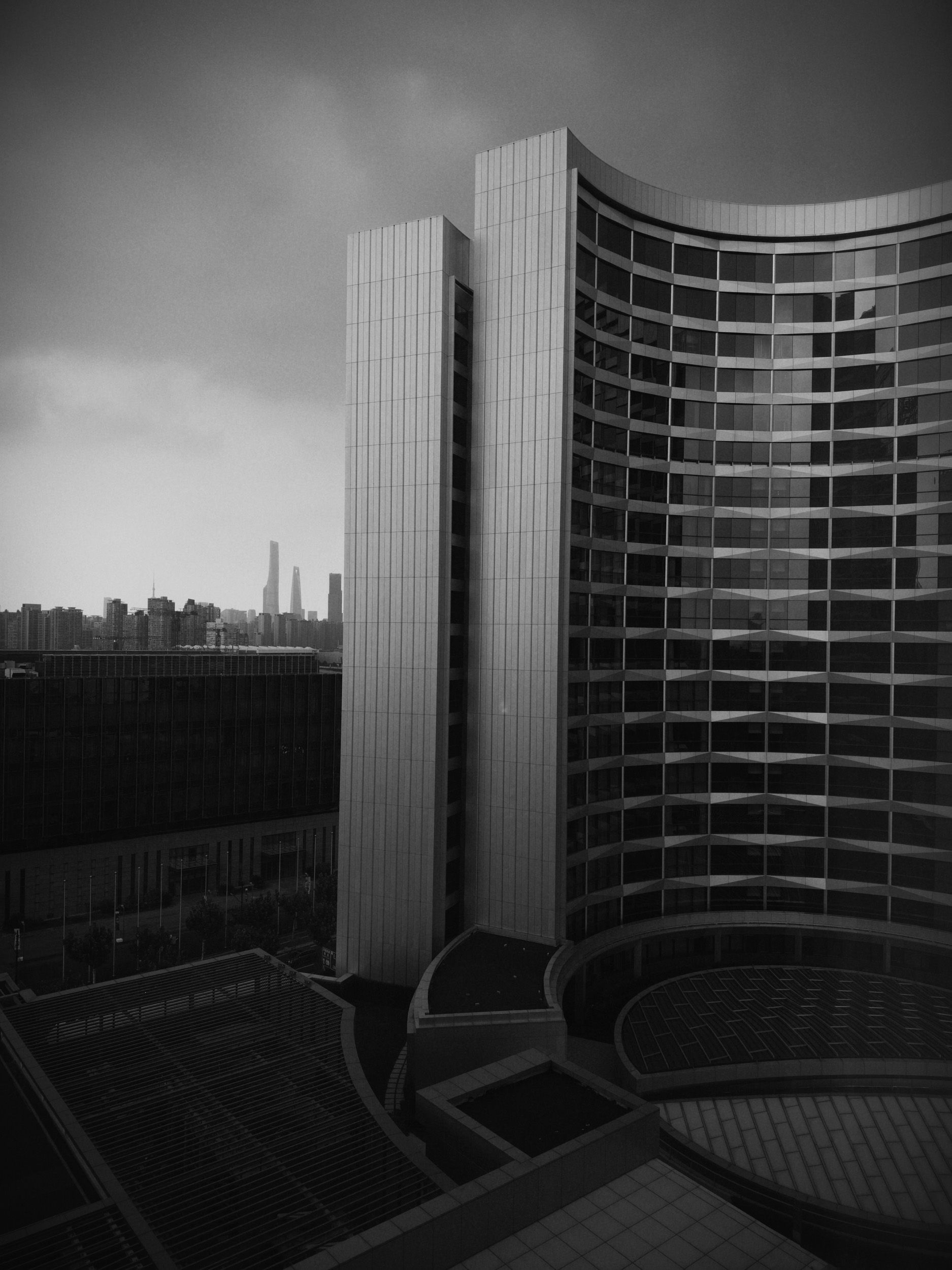A sky scraper in Shanghai, with stormy clouds above it, black and white