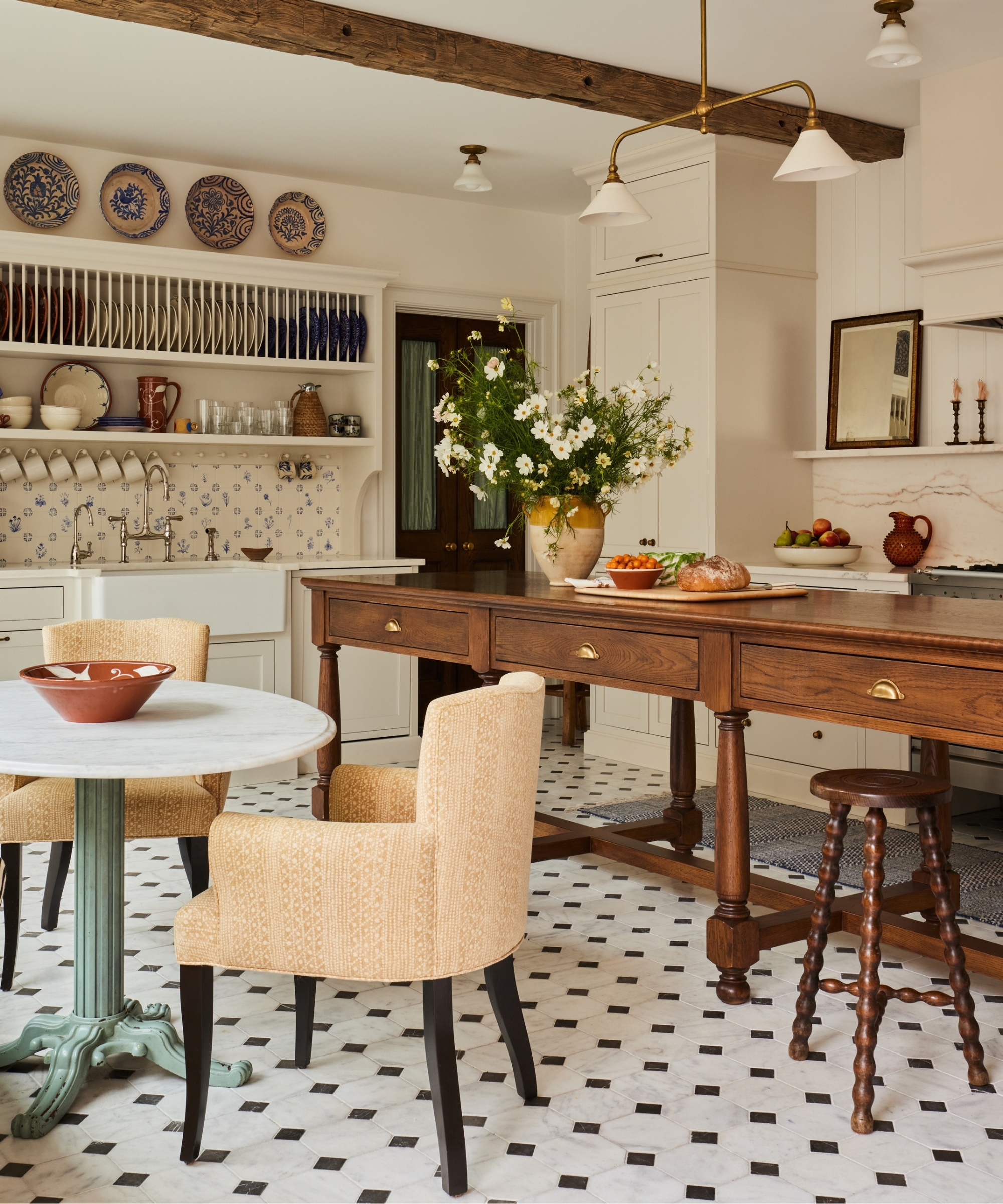 A collected kitchen with neutral cabinets, a wood island, and white floor tiles with black squares in each corner