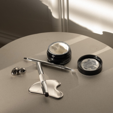 An image of skincare and makeup products strewn on a sun-soaked tabletop.