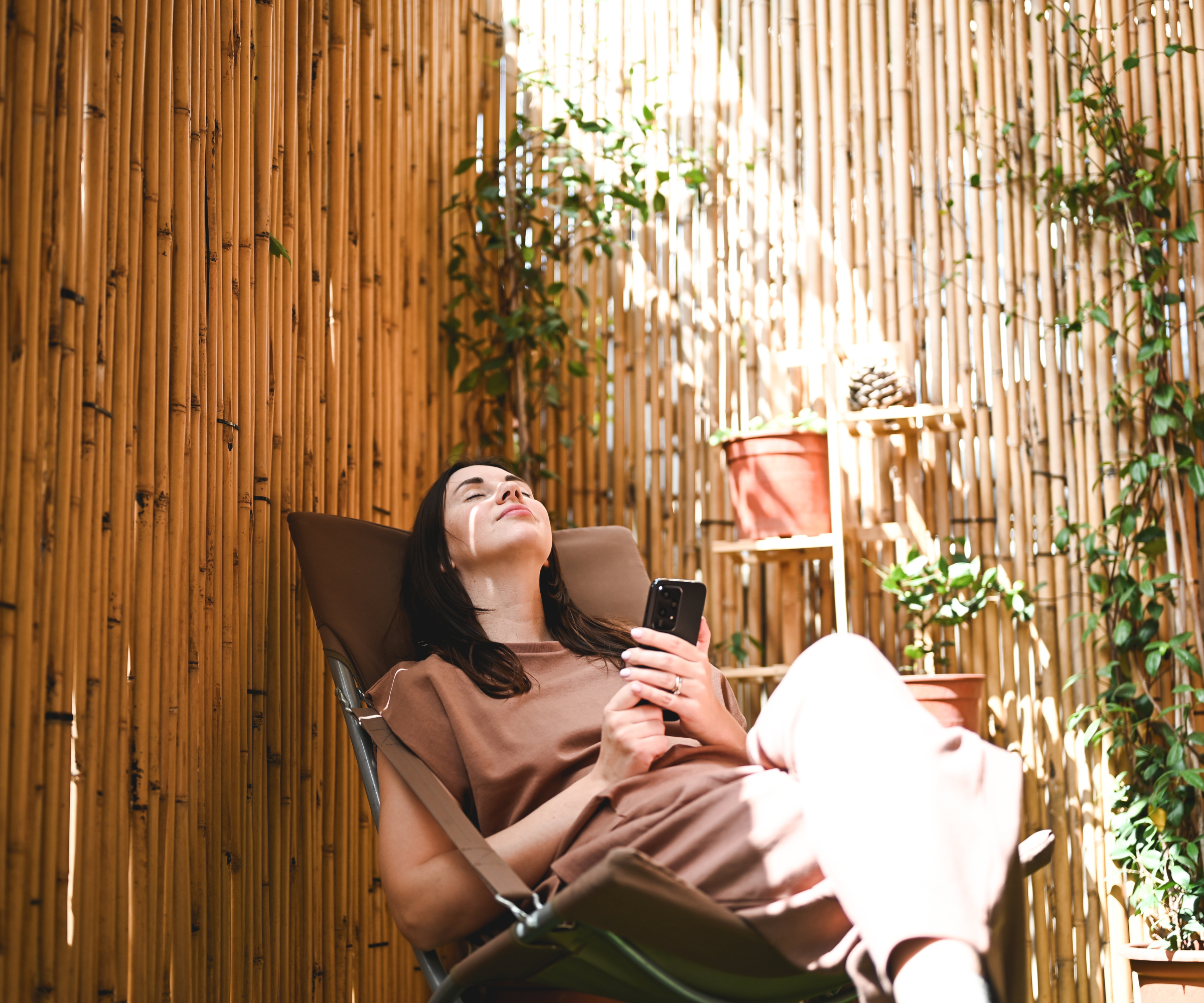 woman sat on chair outside in area screened off with bamboo fence roll