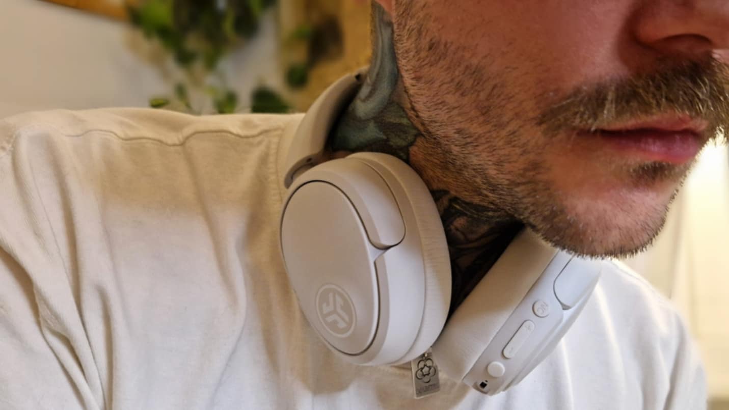 JLab JBuds Lux ANC i vitt runt halsen p&amp;aring; en man.