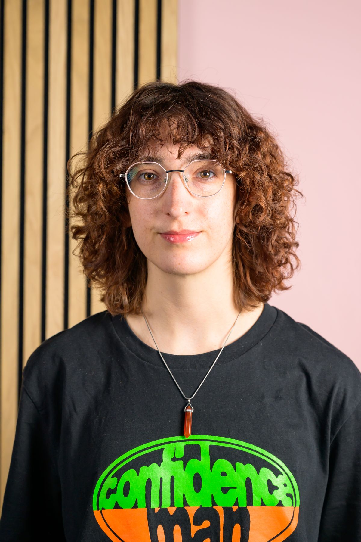 A portrait of Tom's Guide staff writer Erin Bashford, with a split pink and wooden wall in the background