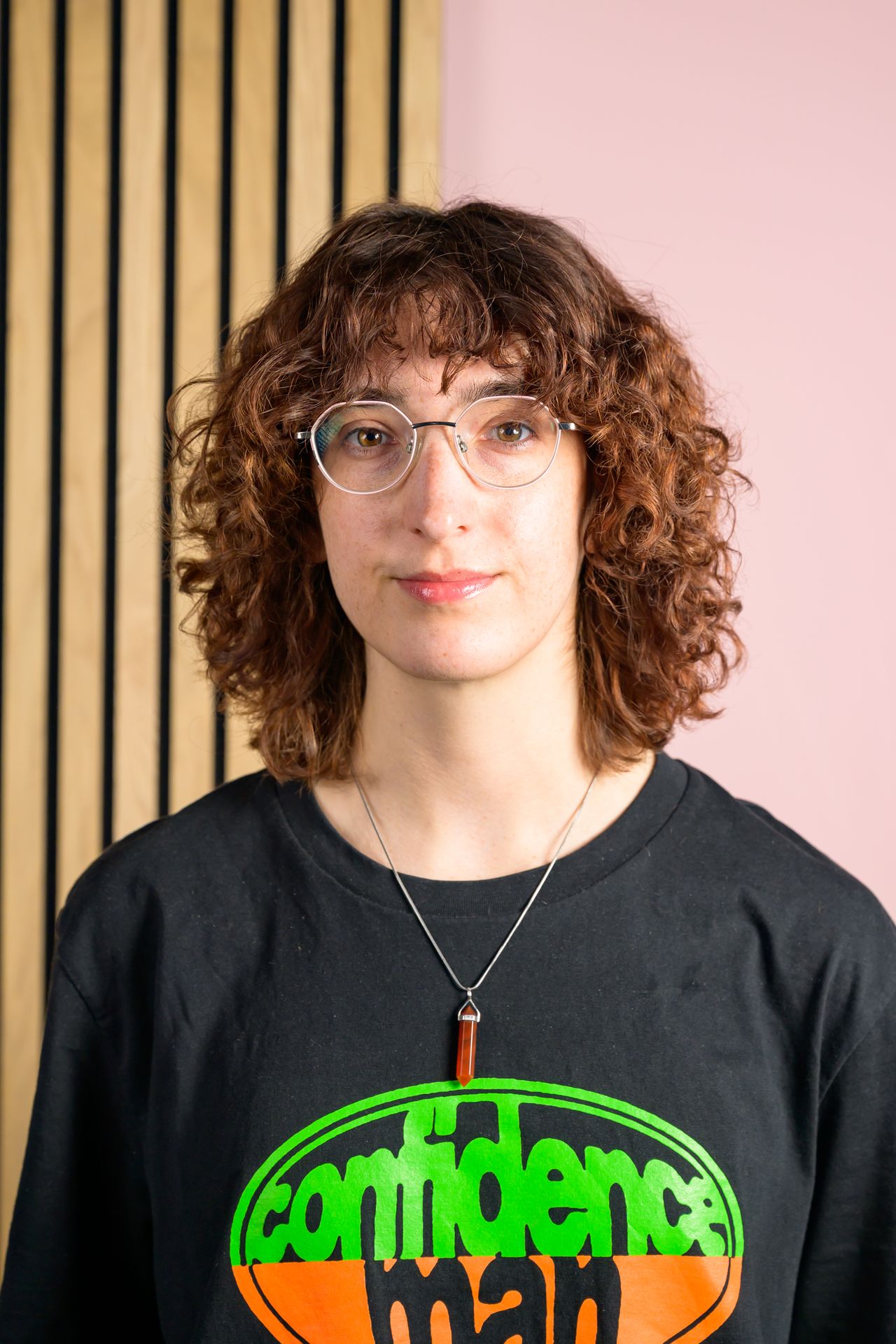 A portrait of Tom's Guide staff writer Erin Bashford, with a split pink and wooden wall in the background