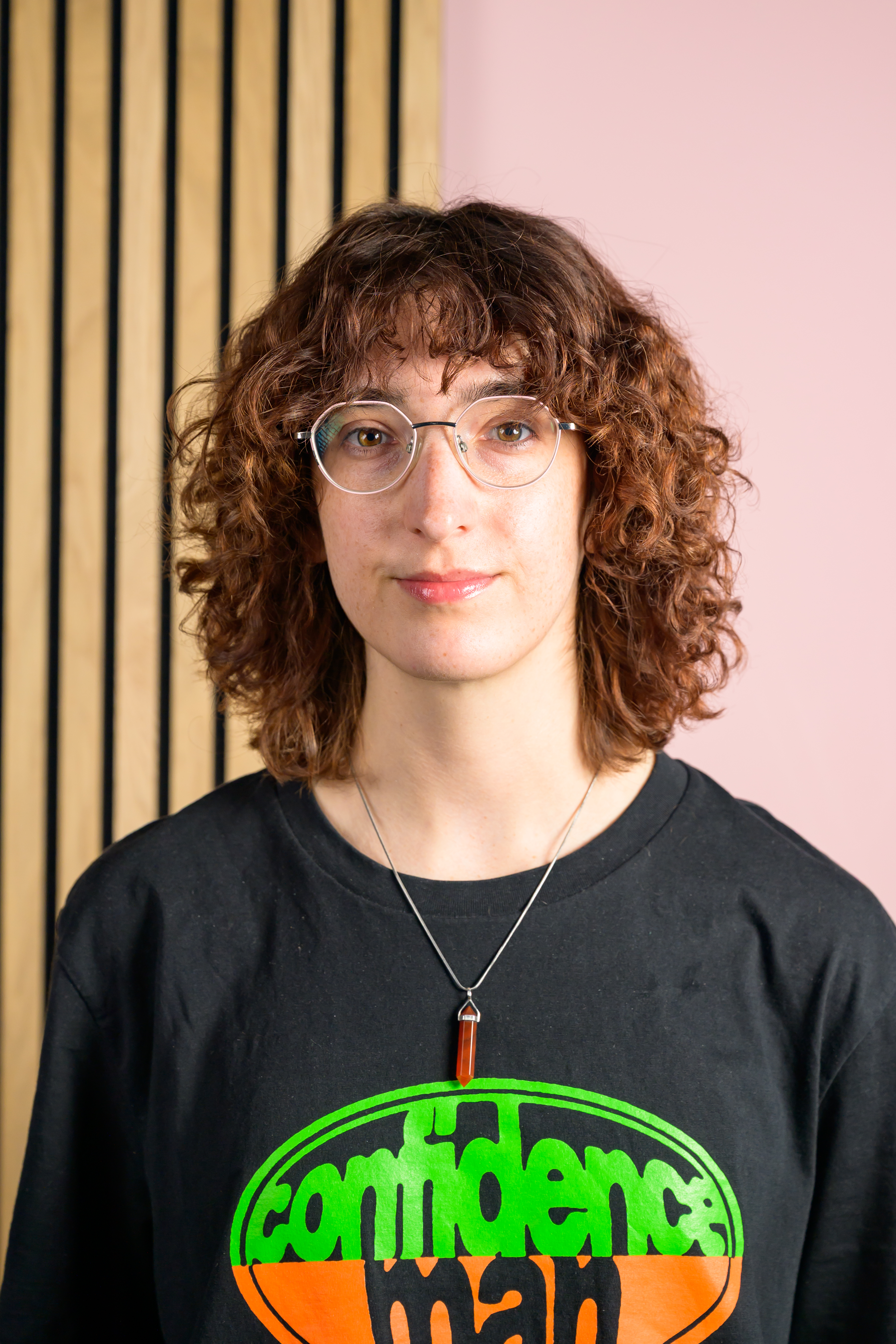 A portrait of Tom's Guide staff writer Erin Bashford, with a split pink and wooden wall in the background