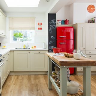 Neutral kitchen with chalkboard wall, red fridge and freestanding island