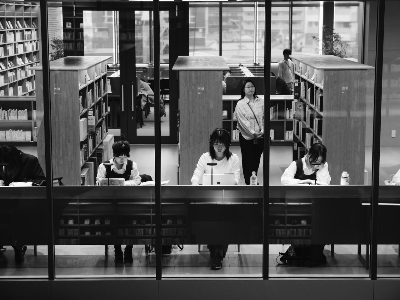 Black-and-white photo of people studying inside a library.