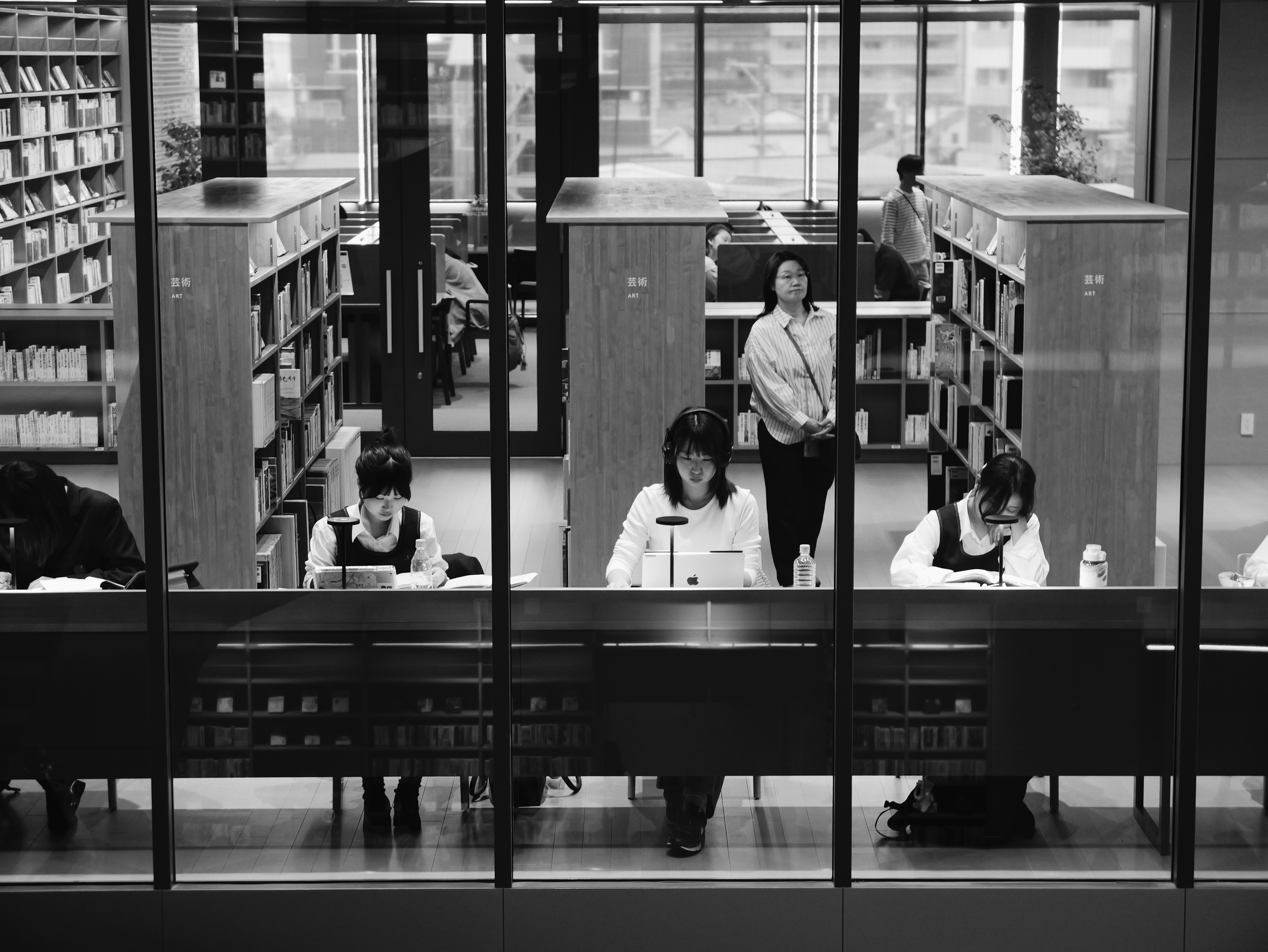 Black-and-white photo of people studying inside a library.