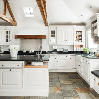 kitchen with white cabinets white wall sun roof and stone flooring