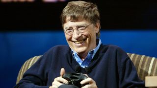 Bill Gates in 2005 holding an Xbox controller and smiling.