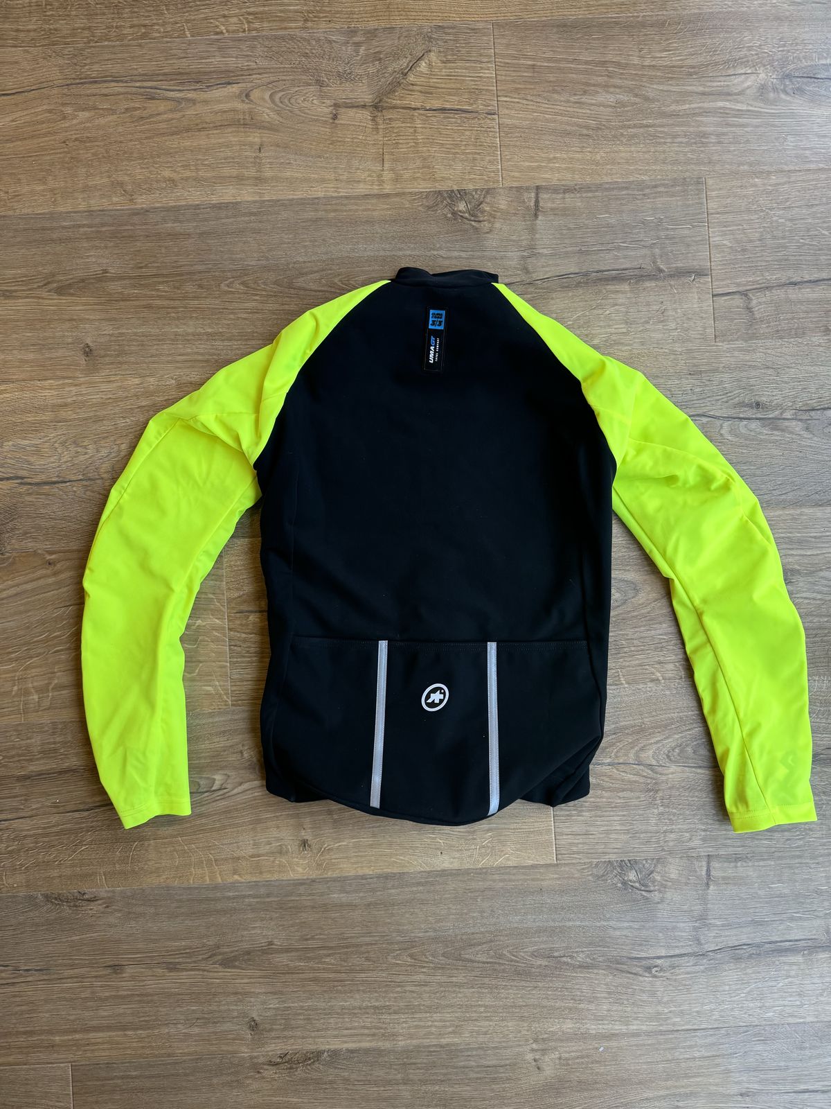 A flat lay jacket with fluorescent yellow arms and a black back with pockets and reflective detail.