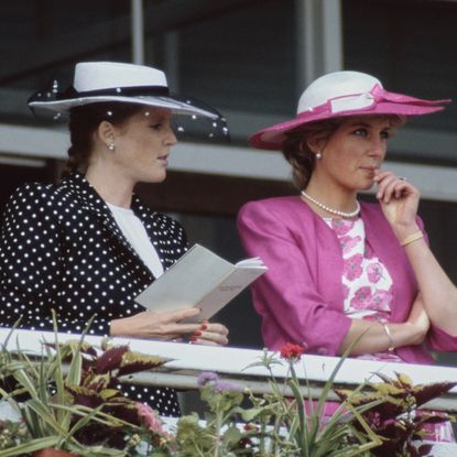 Sarah Ferguson and Princess Diana wearing hats standing along a railing at the Epsom Derby