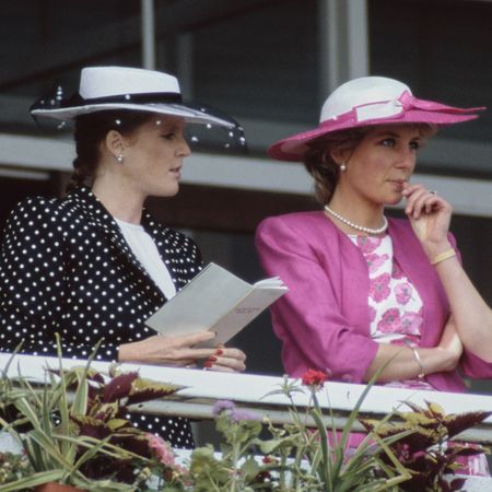 Sarah Ferguson and Princess Diana wearing hats standing along a railing at the Epsom Derby