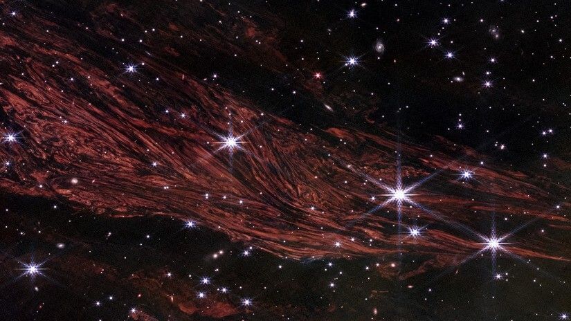 An image of red swirling dust and sparkling stars in outer space