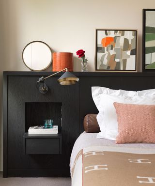 A large black headboard with built in storage and artwork above it