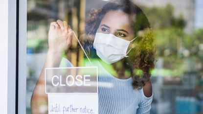 woman flipping a closed until further notice sign