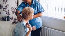 Home caregiver helping a senior woman get dressed in her bedroom