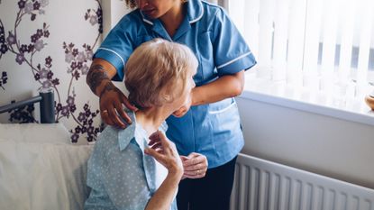 Home caregiver helping a senior woman get dressed in her bedroom