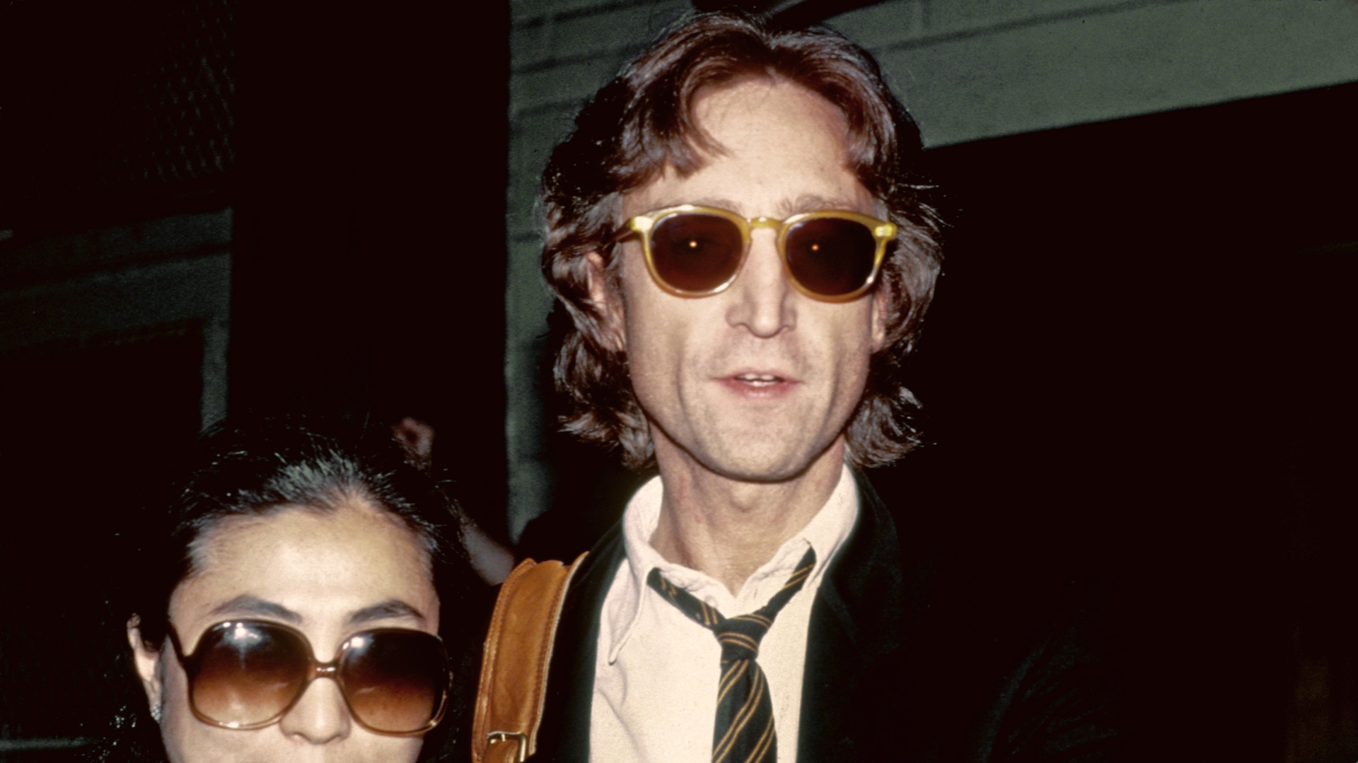Former Beatle John Lennon and his wife Yoko Ono pose for a portrait outside of the Times Square recording studio in August 1980 in New York City, New York.