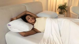 A woman sleeping comfortably and smiling using the Purple Harmony pillow