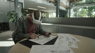 Photo of a person wearing a Meta Quest 3 and using the Logitech MX Ink stylus