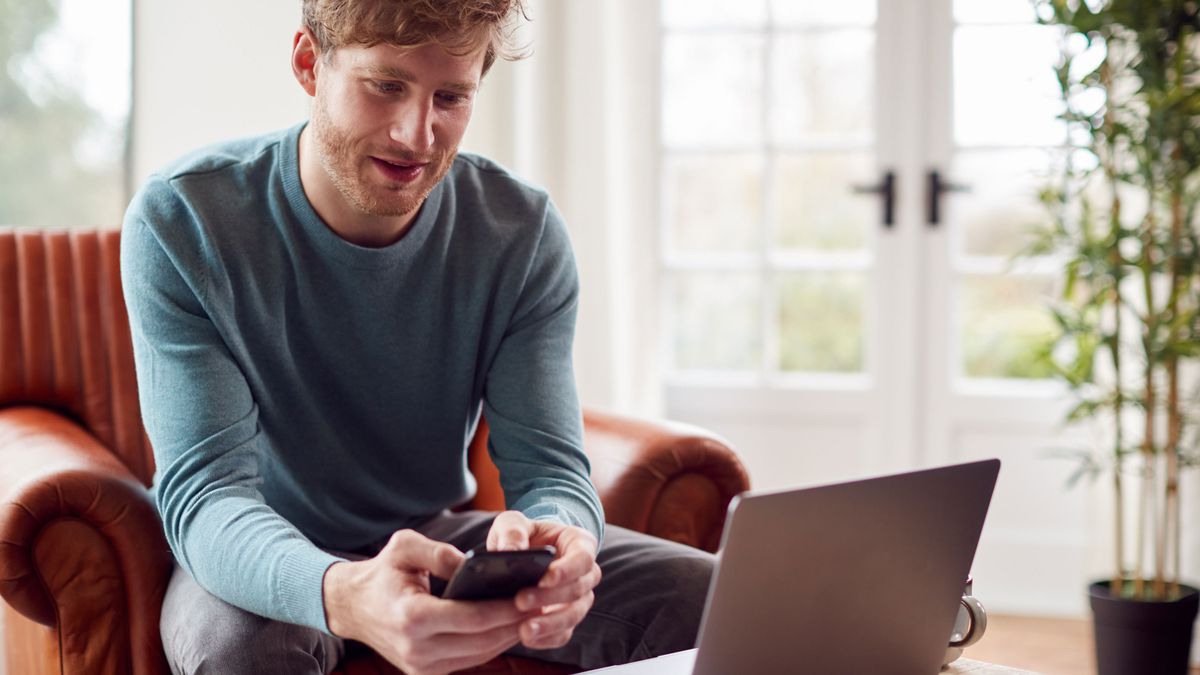 Man Working From Home Using Laptop And Mobile Phone