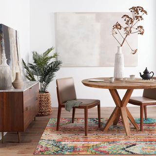 A bohemian style multi-colored rug sitting on top of a wooden table and chairs