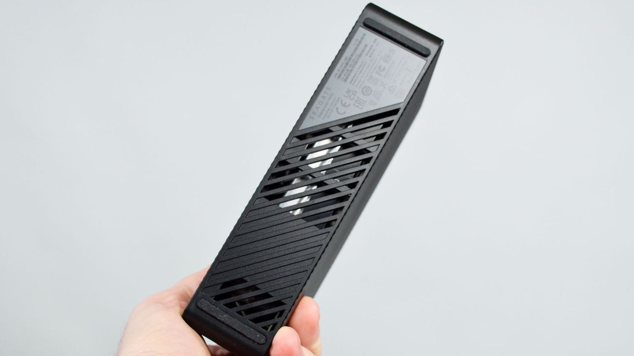 A masculine hand holding a Seagate Expansion external desktop hard drive