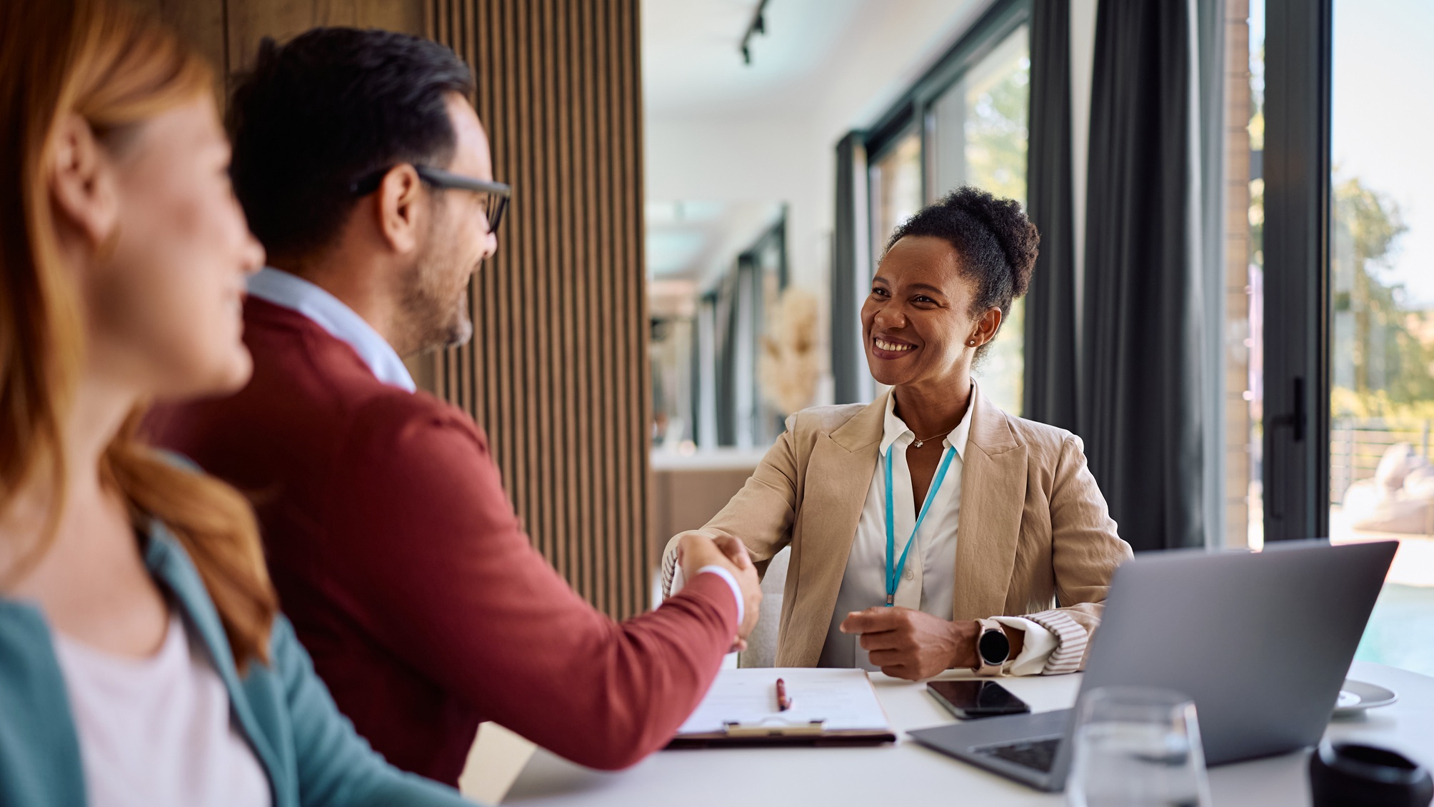 An adviser smiles as she shakes hands with a new client in her office.