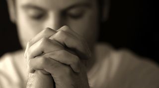 A man praying in black and white.