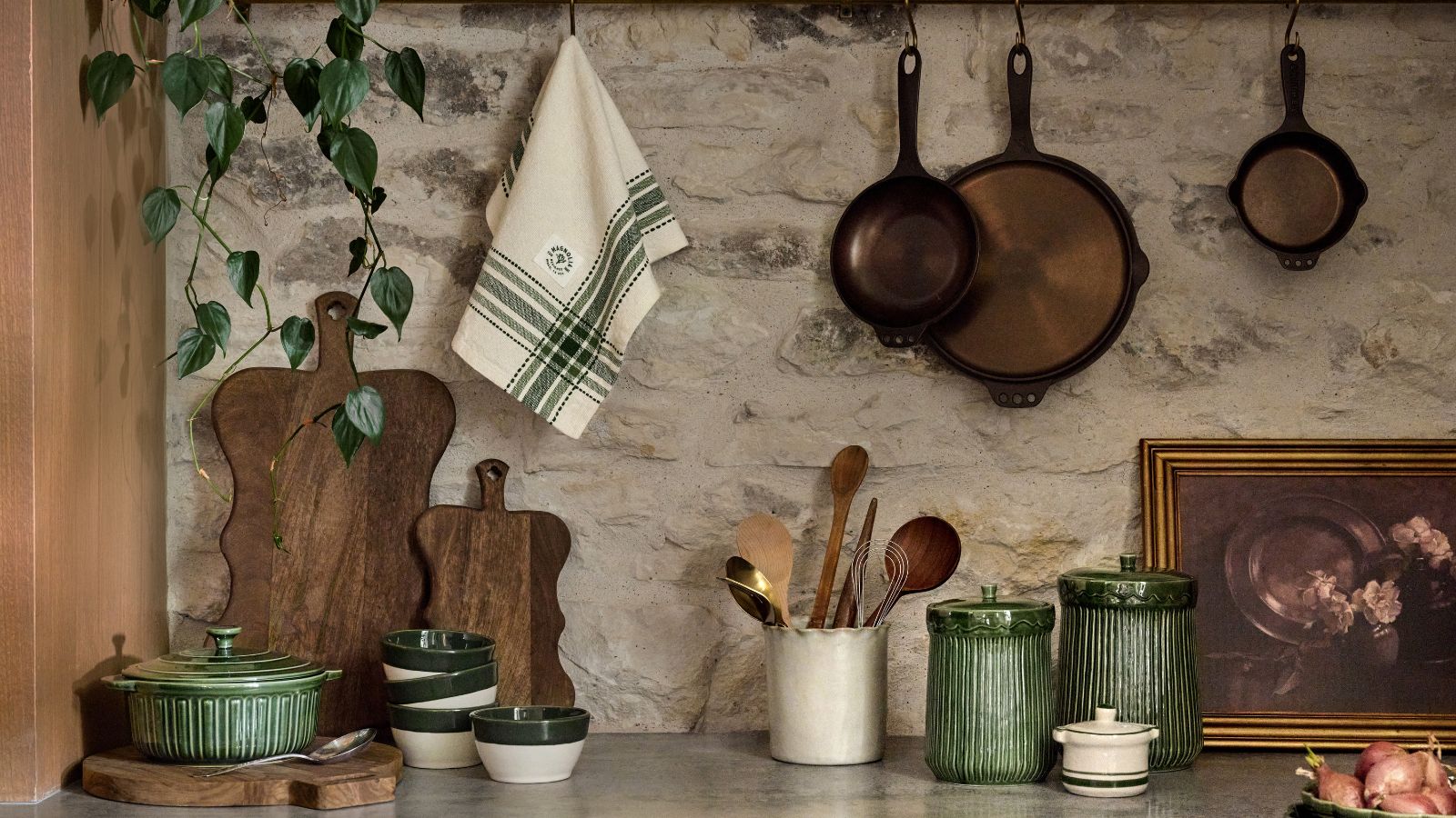 Kitchen countertop with wood chopping boards, copper pans, ceramic jars and utensils