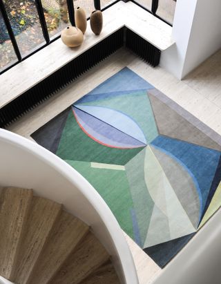 An aerial view of a carpet featuring colourful geometric patterns by Umberto Riva, shown on stone floor